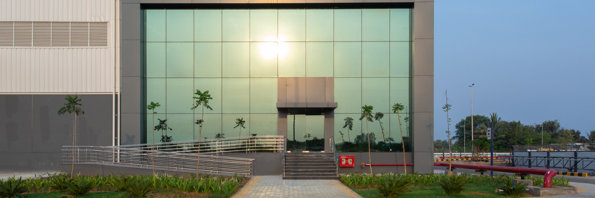 Warehouse entrance with a glass facade reflecting the sunlight.
