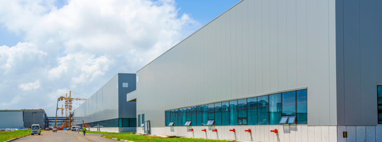 Warehouse side elevation with blue windows and a paved access road.