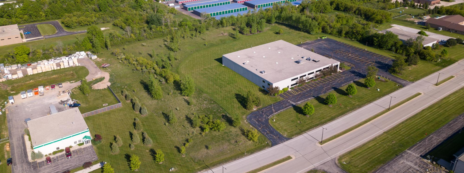 Aerial view of an industrial building beside a road and grassy grounds.