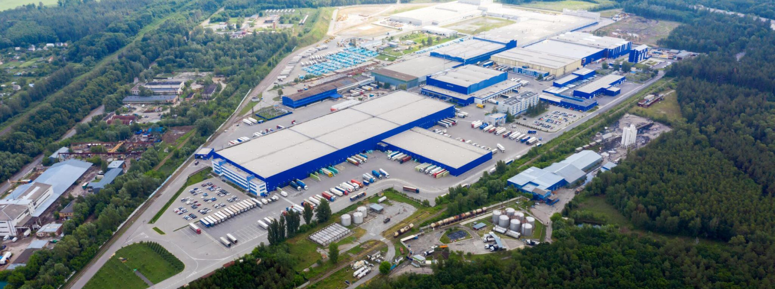 Aerial view of an industrial park with blue-trimmed warehouses and internal roads.