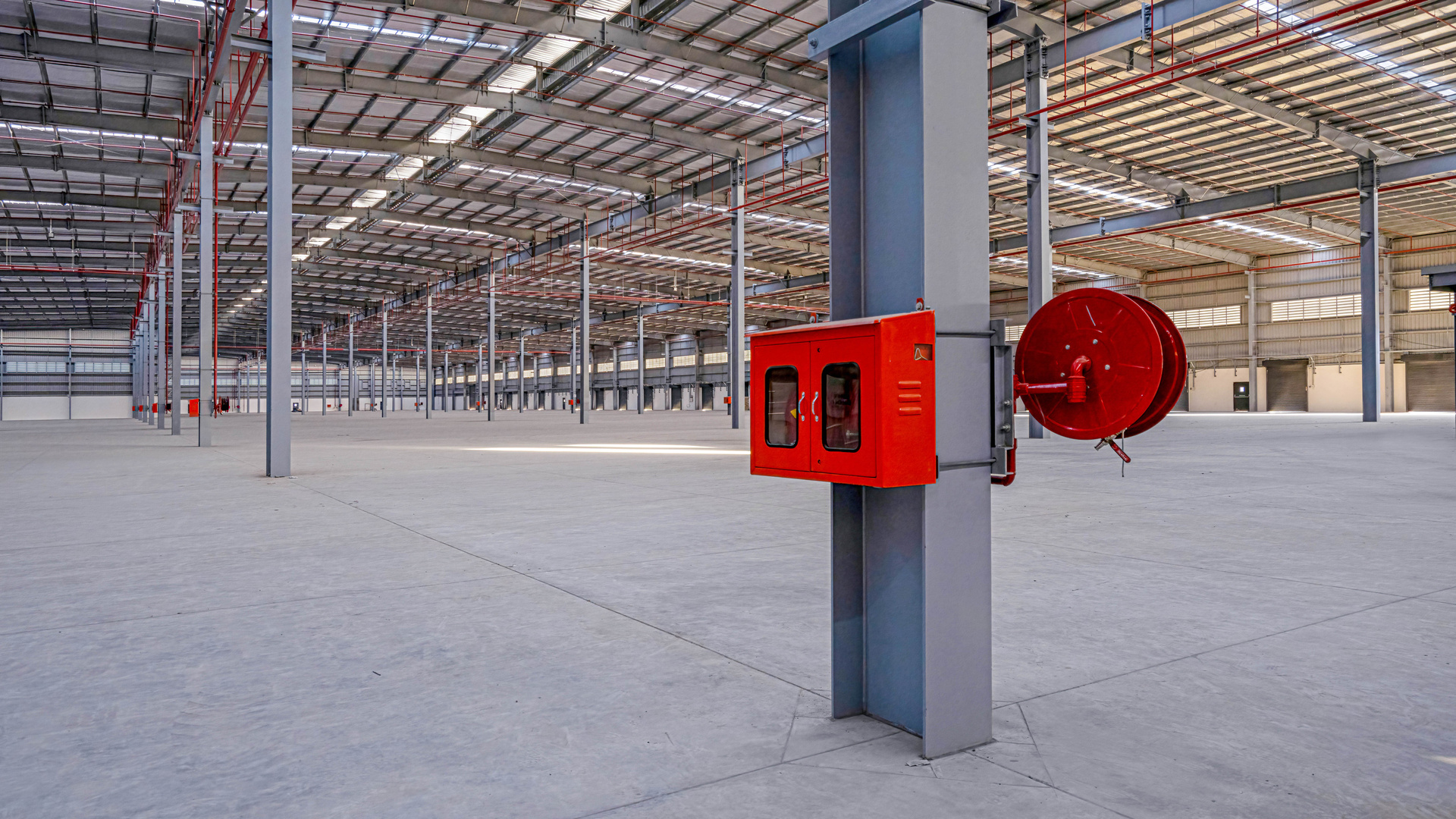 Fire hose reel and fire equipment cabinet mounted on a warehouse column.
