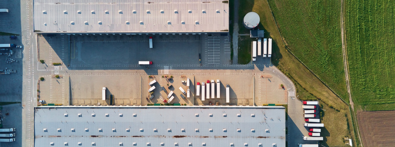 Overhead view of trucks and trailers between two warehouse buildings.