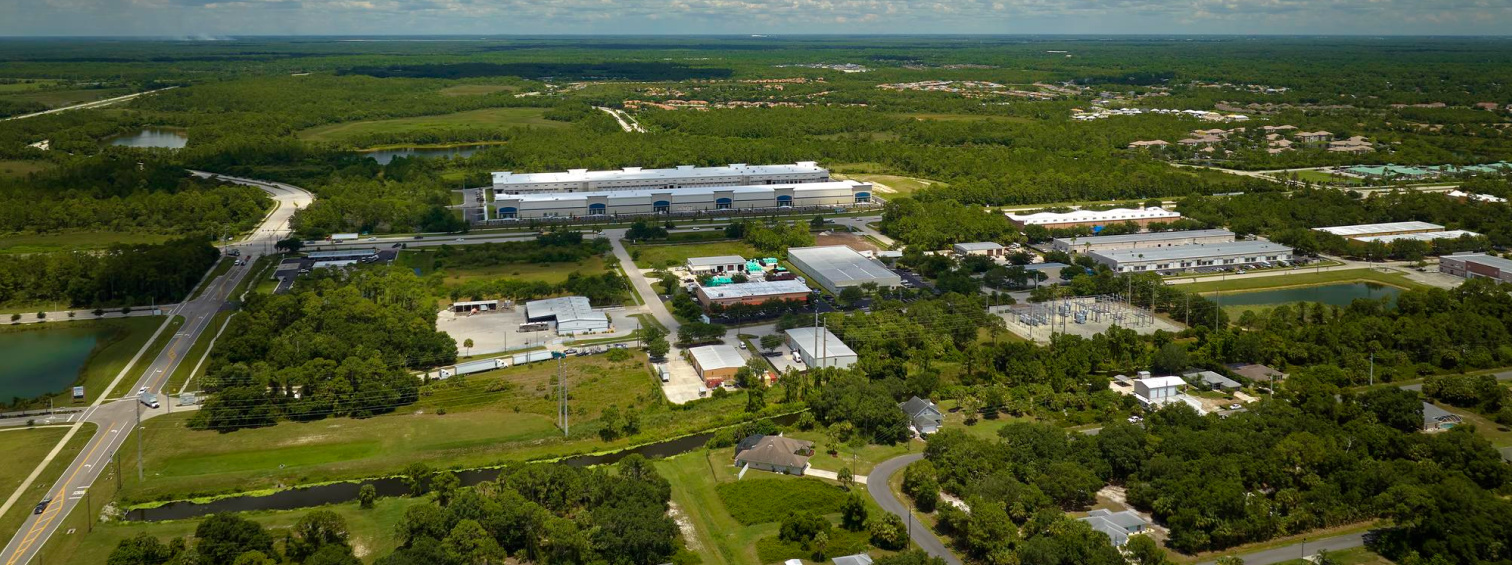 Aerial view of an industrial campus surrounded by green land and trees.